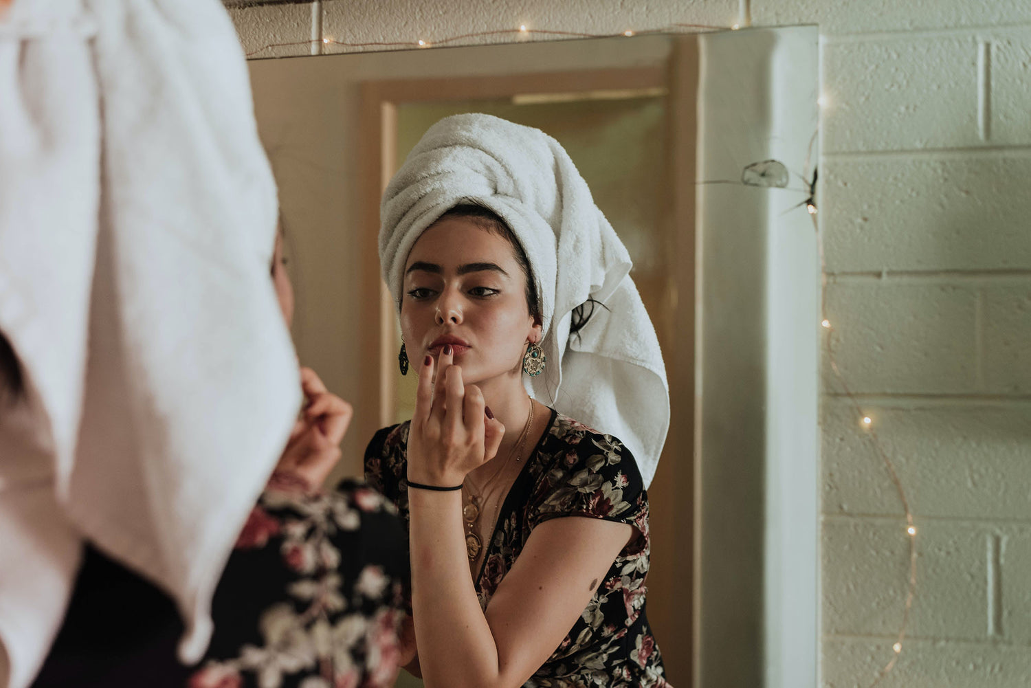 woman in bathroom looking at her skin concerns before seeing Dr Jinah Yoo